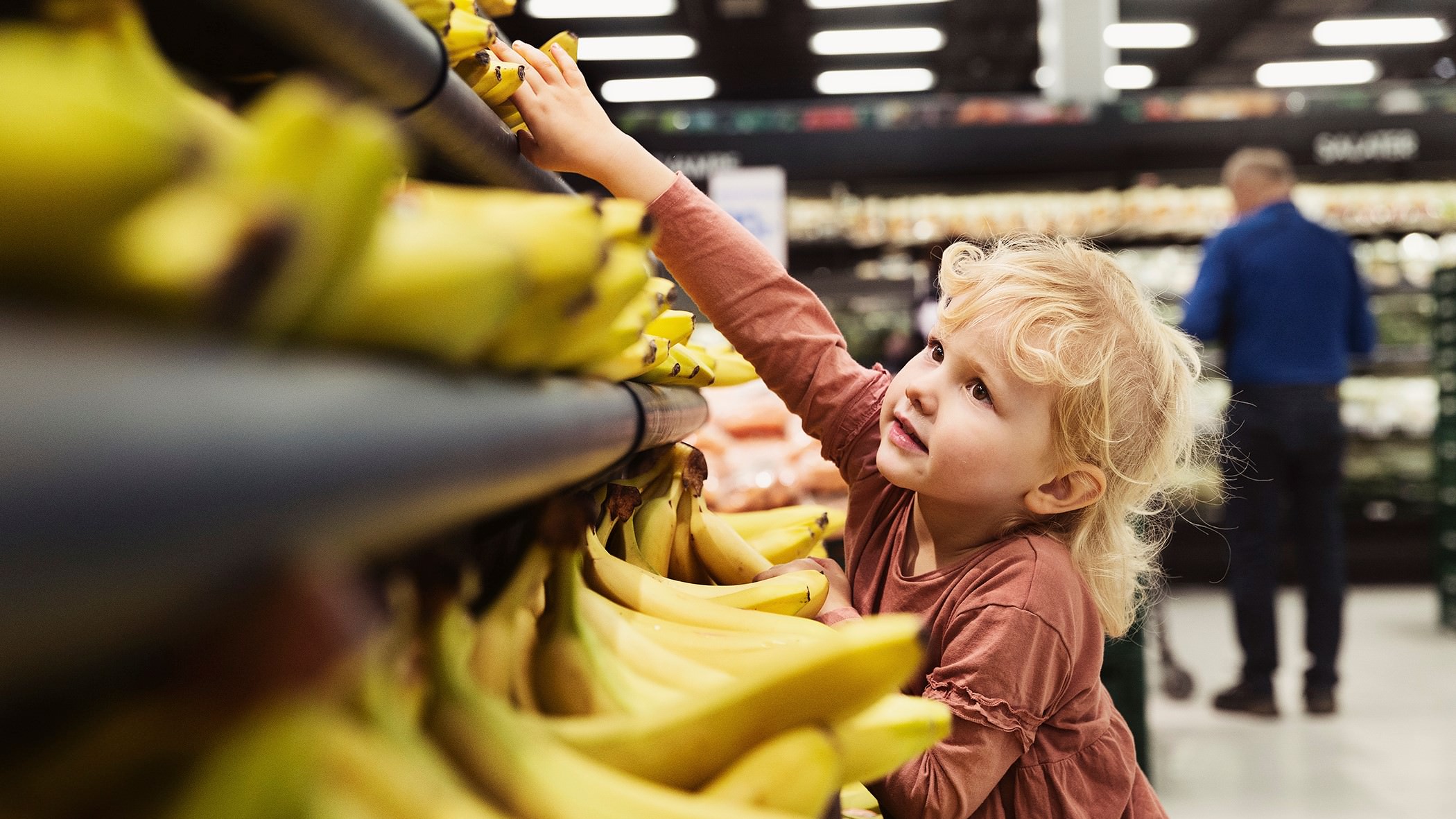 Barn rækker ud efter banan i butik