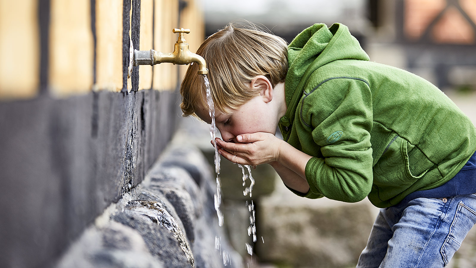 En dreng drikker af vand fra en vandhane
