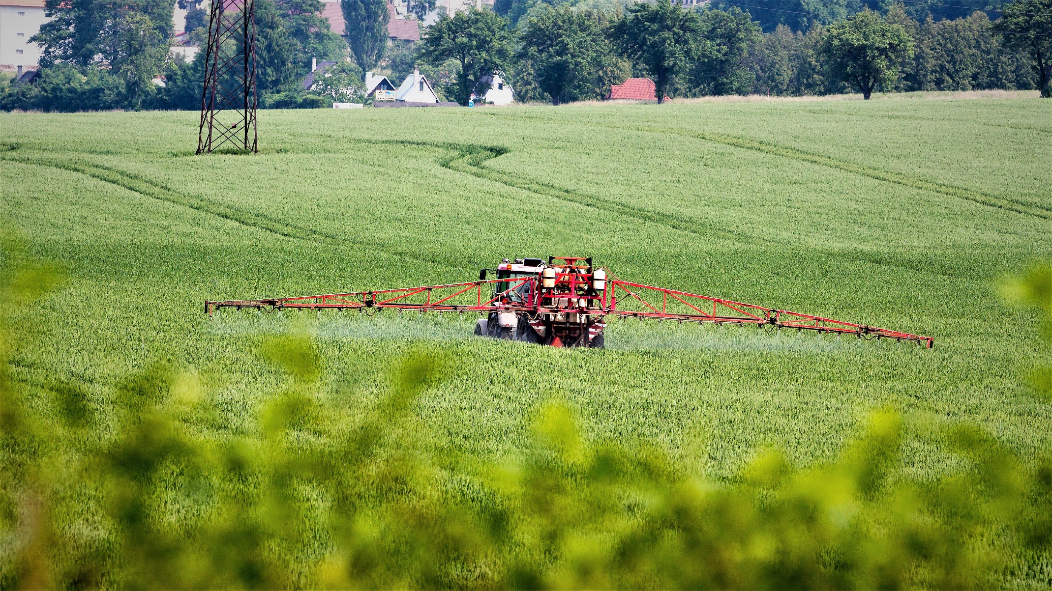 En traktor kører hen over en mark og sprøjter den med pesticider