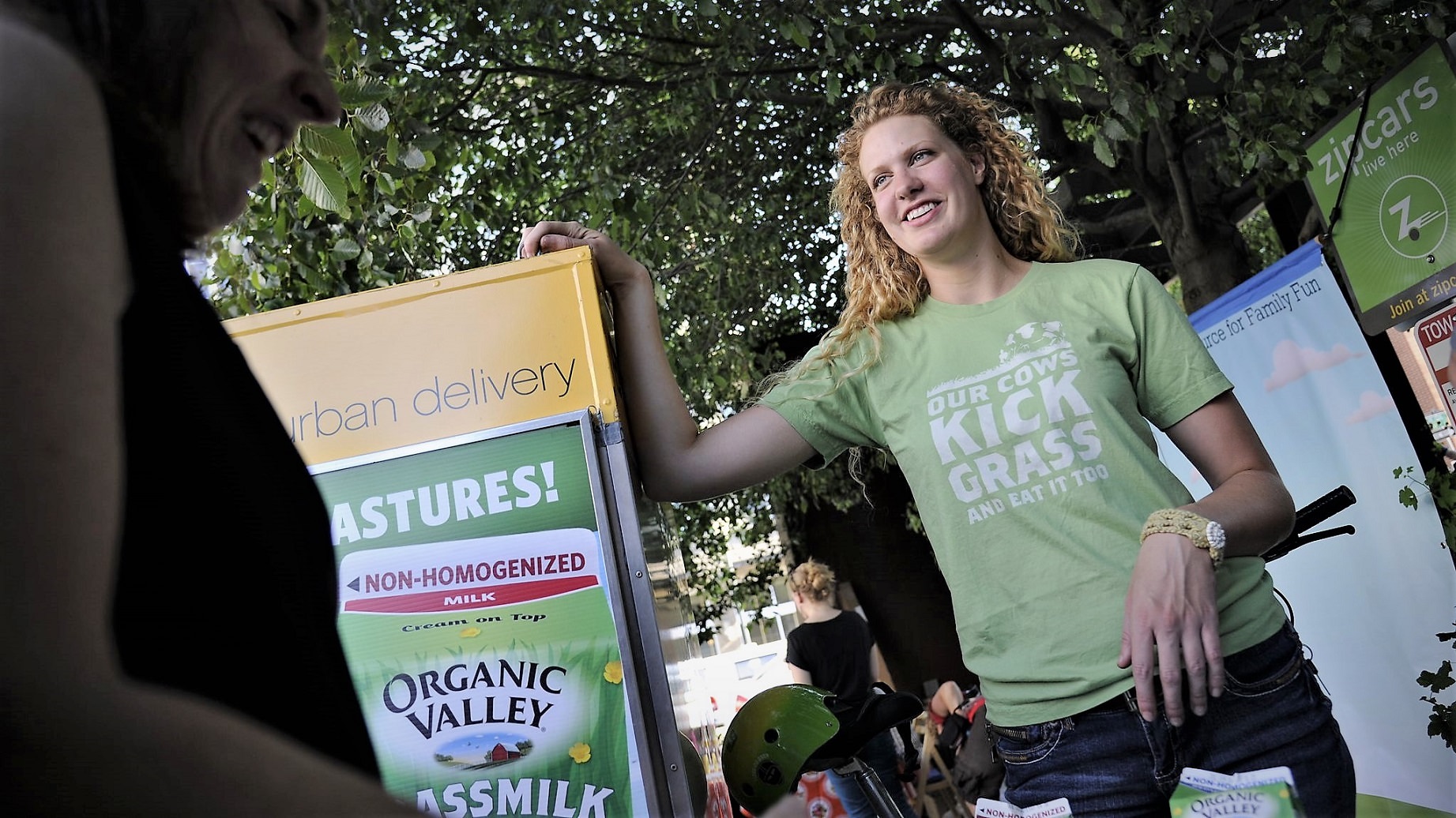 En kvinde står ved en bod, hvor der reklameres for Organic Valleys øko-mælk