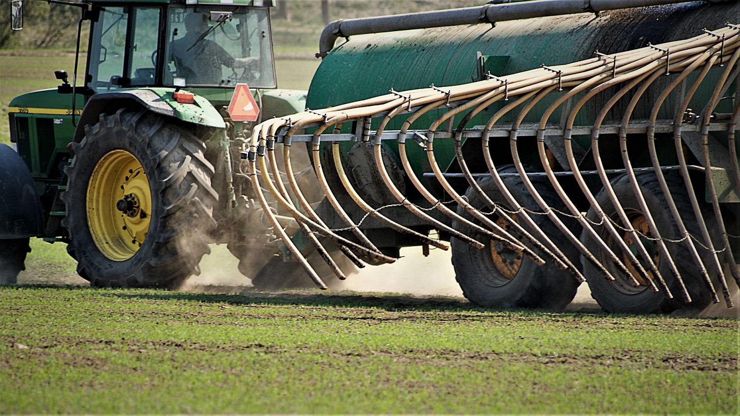 En traktor spreder gødning på marken