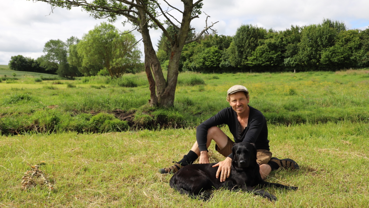 Frank Erichsen sidder på engen med sin hund Kaisa