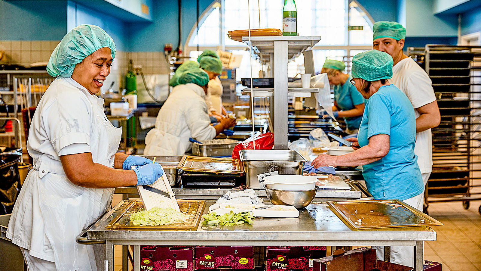 Køkkenpersonale på Bispebjerg og Frederiksberg Hospital står i køkkenet og tilbereder mad.