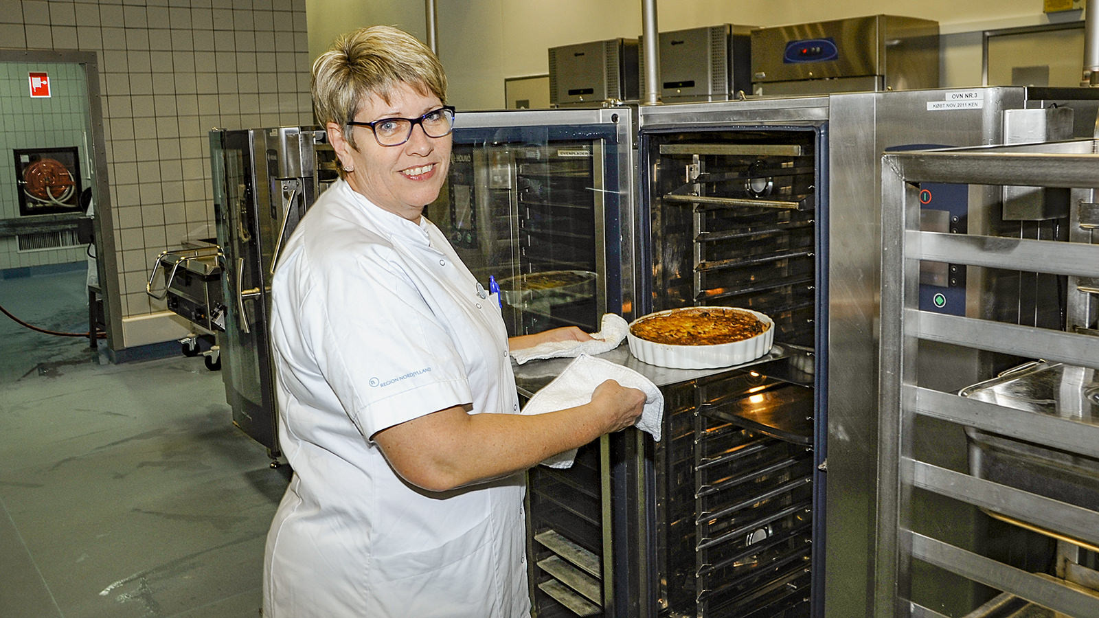 Marian Bloch Larsen, økonoma og afsnitsleder i køkkenet ved Aalborg Universitetshospital i Thisted, er ved at tage en tærte ud af ovnen i hospitalskøkkenet.