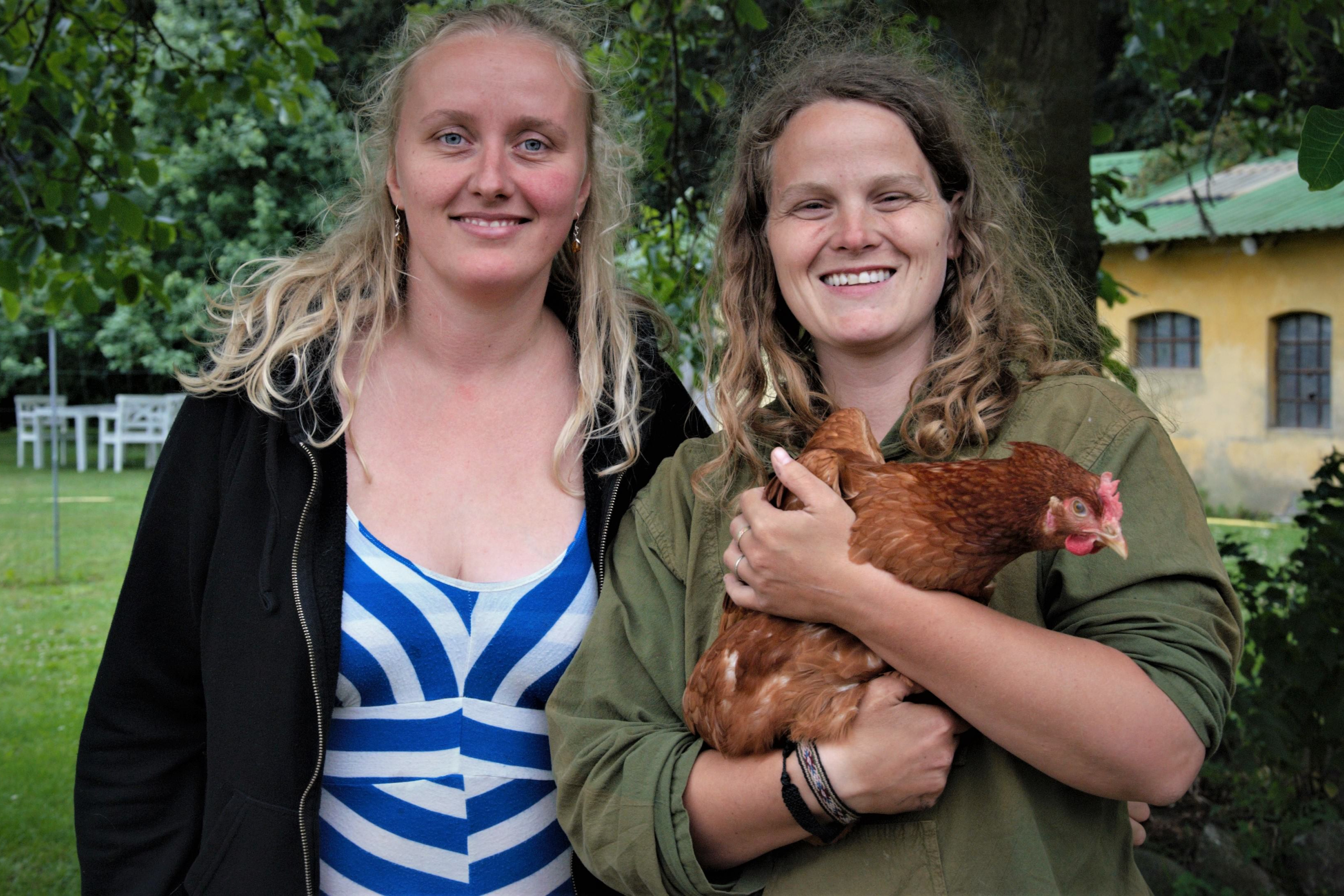 Martha Marie Jensen og Camilla Varming Nielsen står med en høne i deres baghave