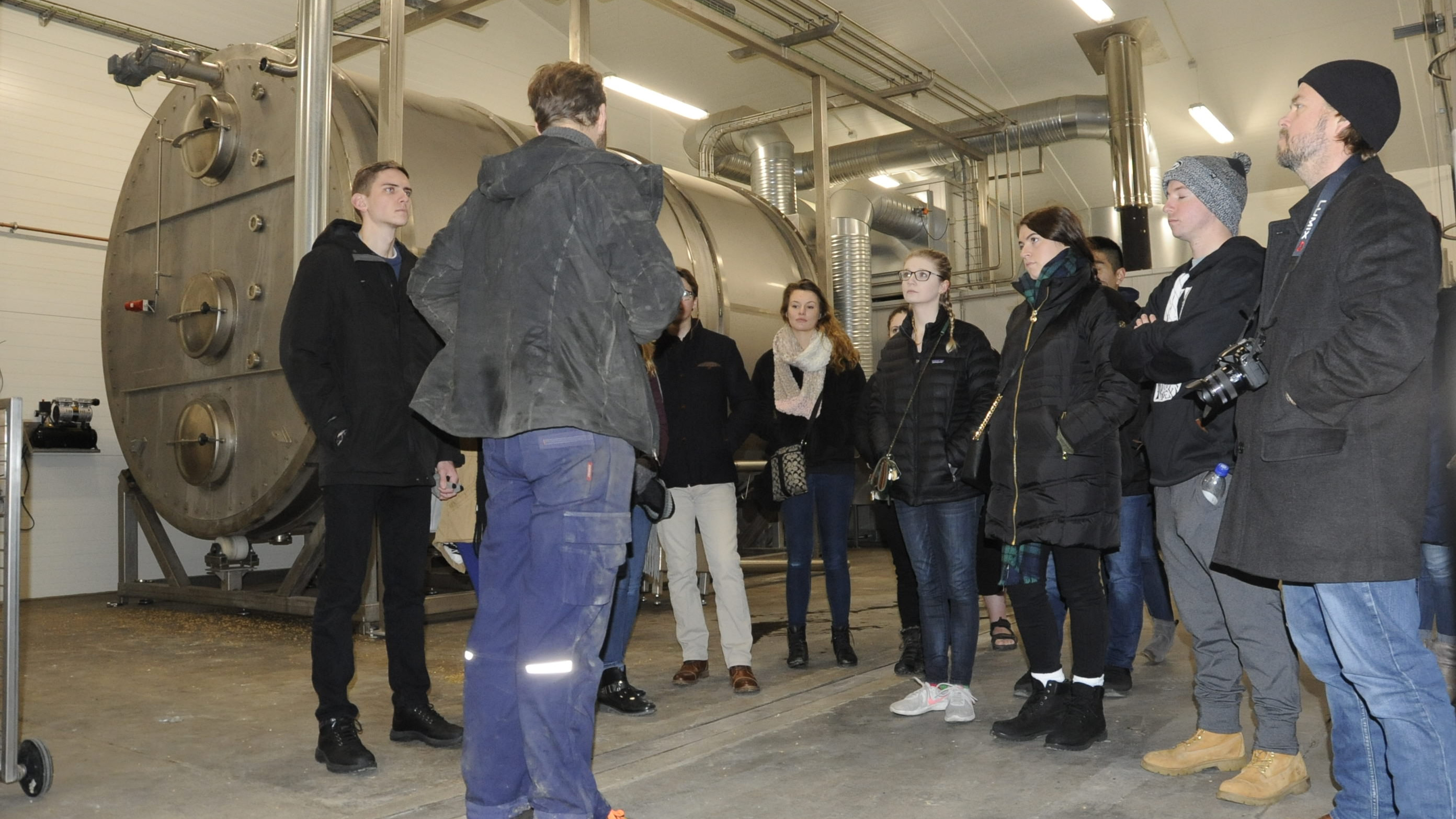 Andreas Poulsen står i gårdmalteriet og fortæller en gruppe amerikanske antropologistuderende om, hvordan korn bliver forvandlet til malt, som bliver brugt til brygning af øl.