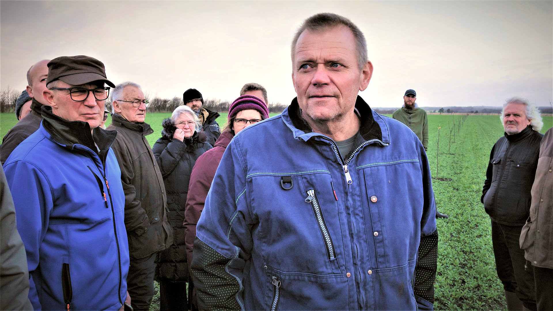 Bjarne Larsen står med en masse folk omkring sig på sin mark, hvor han for nylig har plantet træer