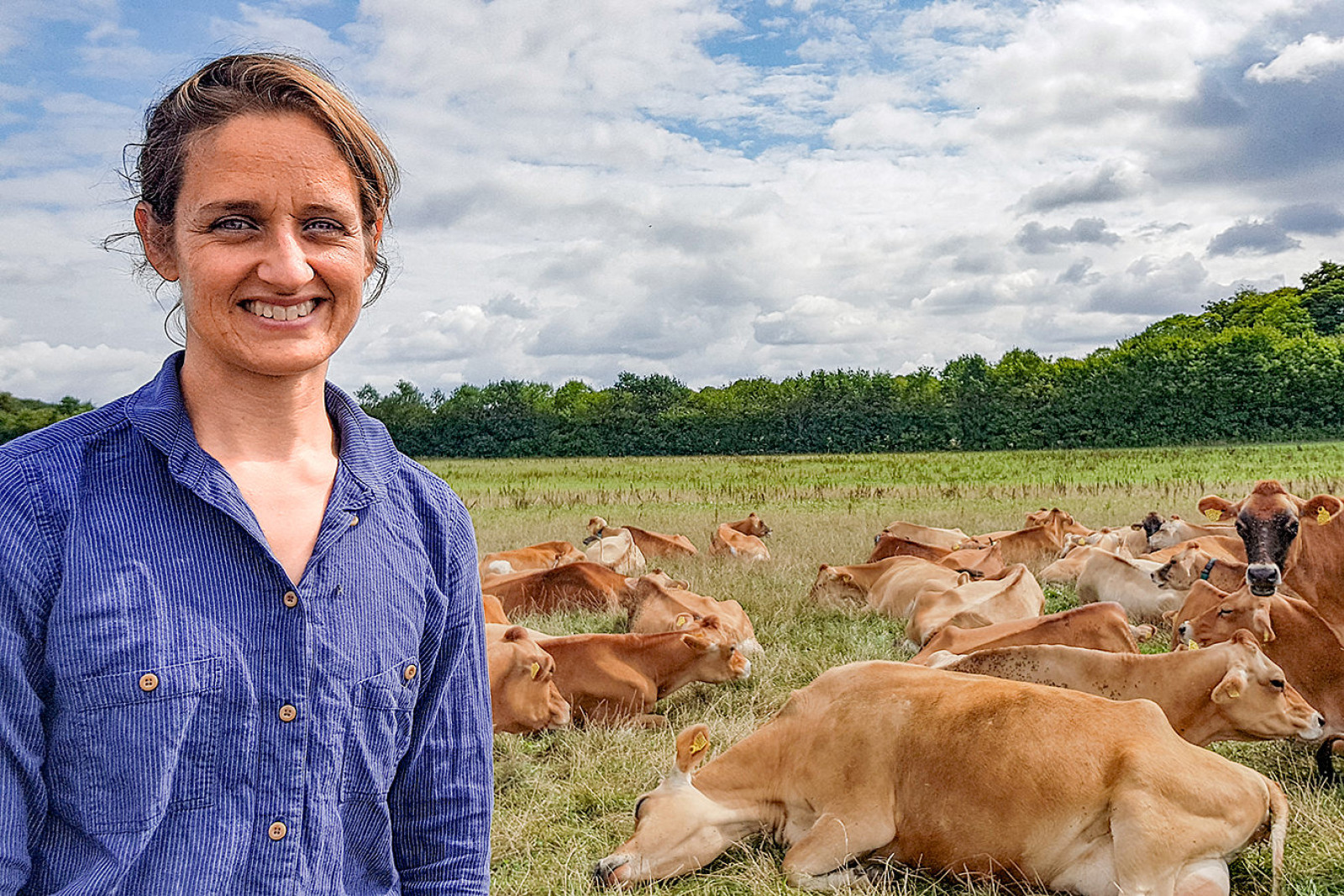 Kristine Dalbach står foran  en flok liggende køer på græs.