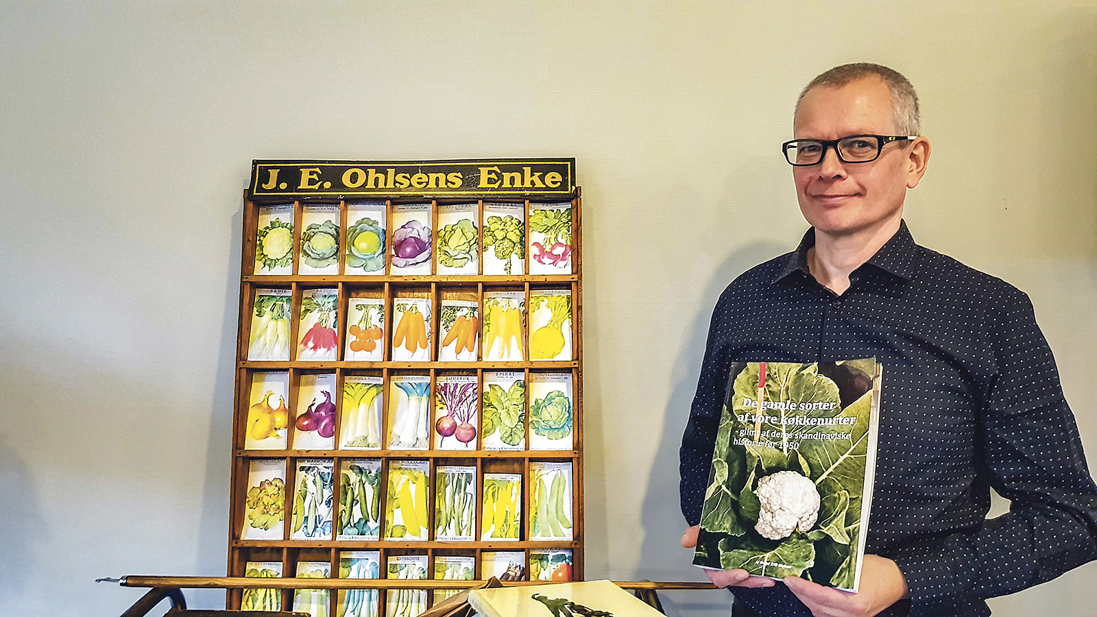 Svend Erik Nielsen står med bogen 'De gamle sorter af vore køkkenurter'