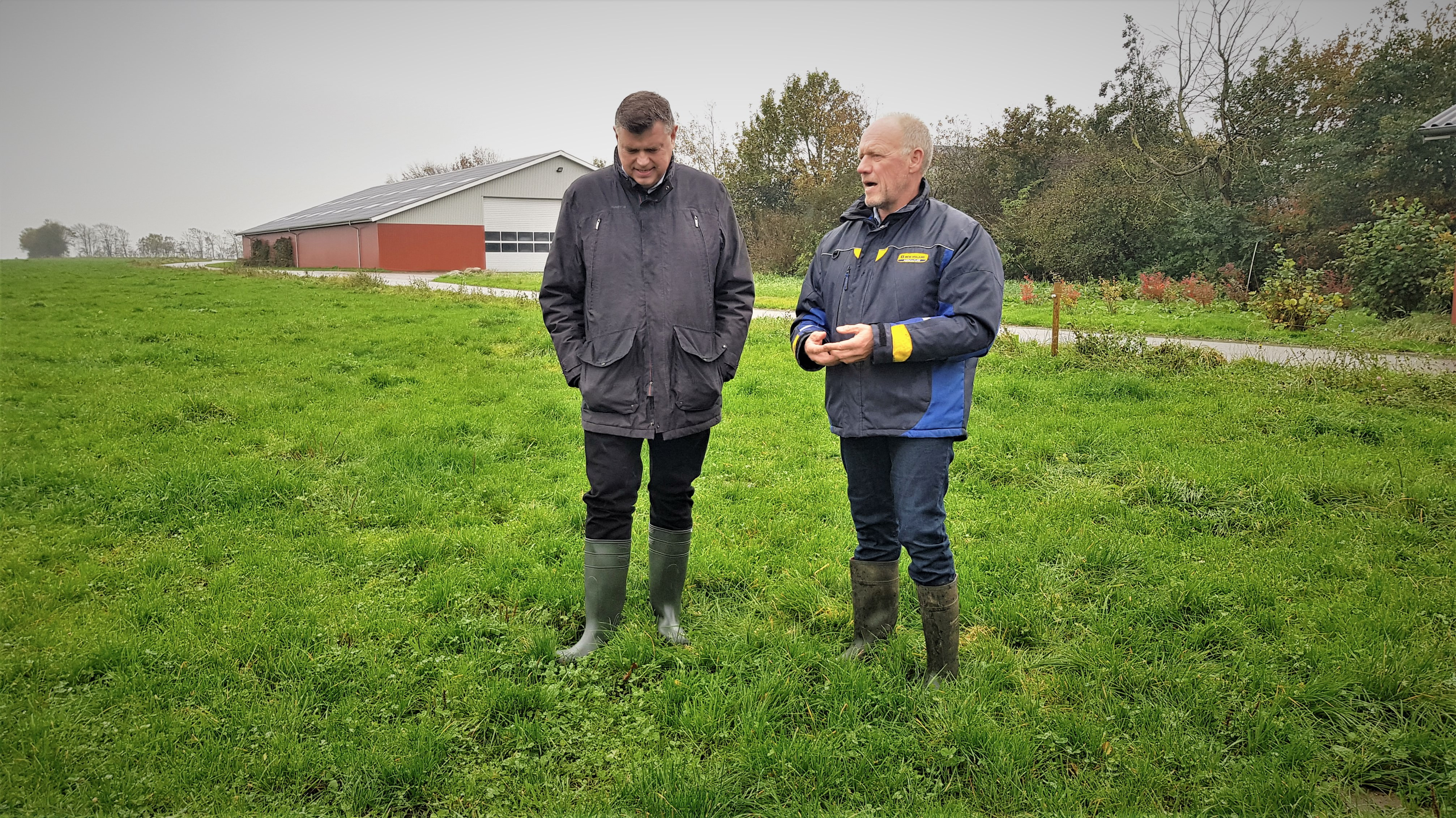 Fødevareminister Mogens Jensen står på en græsmark med landmand Jens Krogh, der giver rundvisning på sin gård